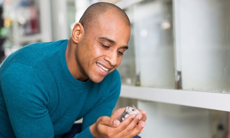 A person wearing blue tshirt holding hamster